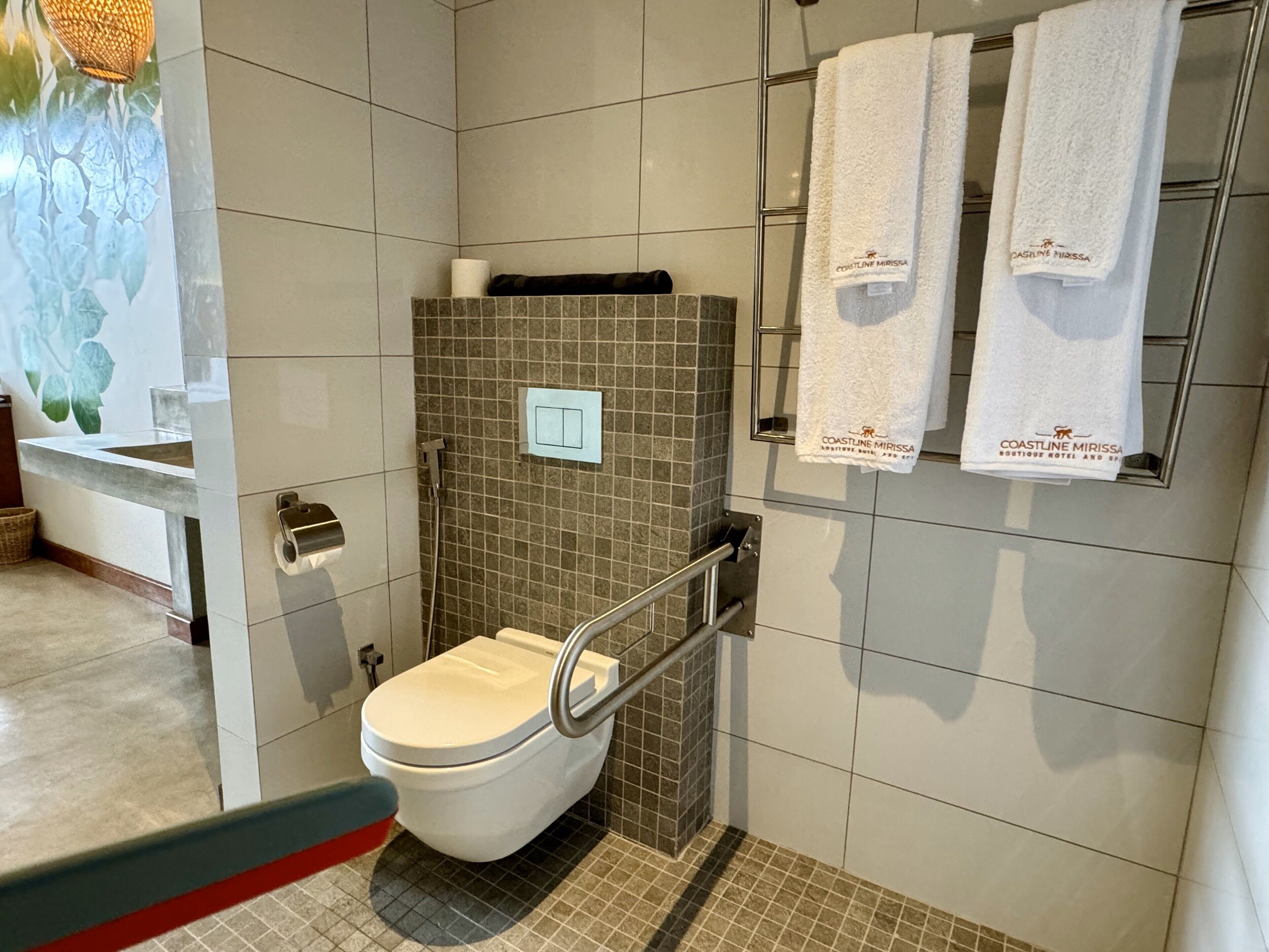 Ein modernes Badezimmer mit Toilette, Dusche und einem Handtuchhalter mit zwei Handtüchern.