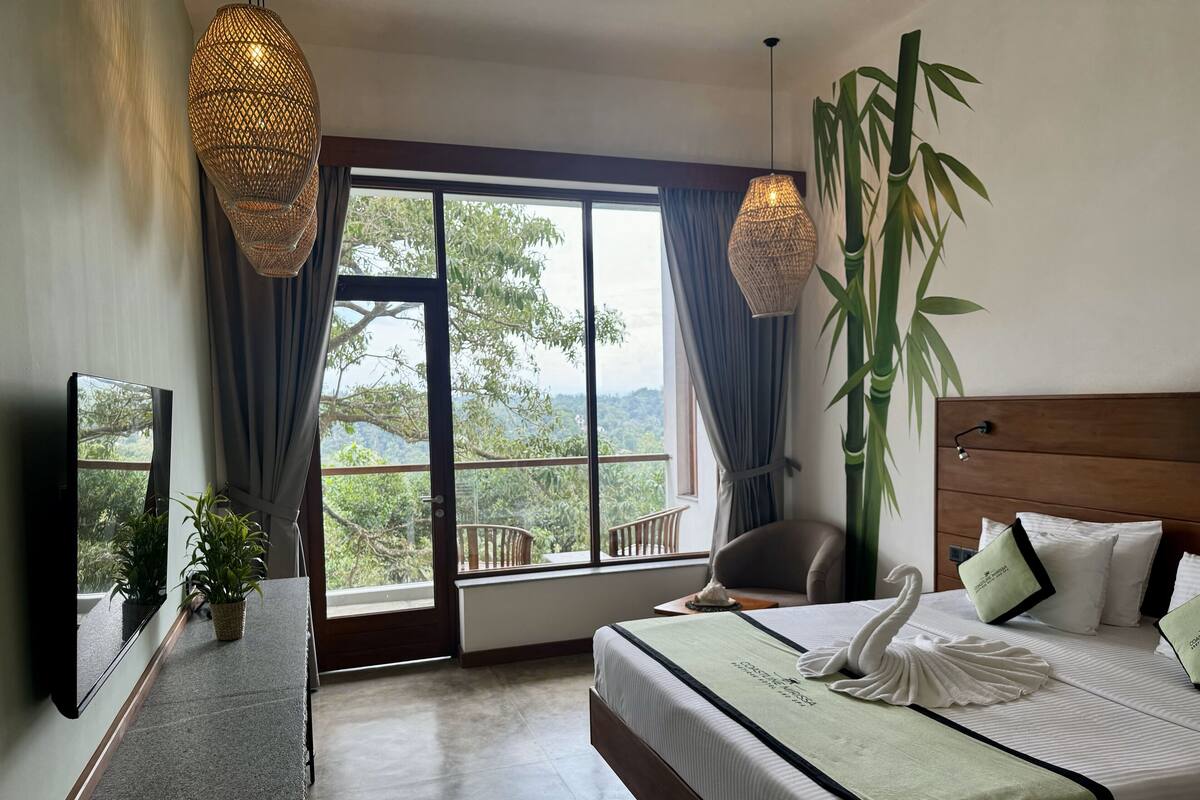 Habitación de hotel con una cama grande, televisión, escritorio y vistas al exterior.