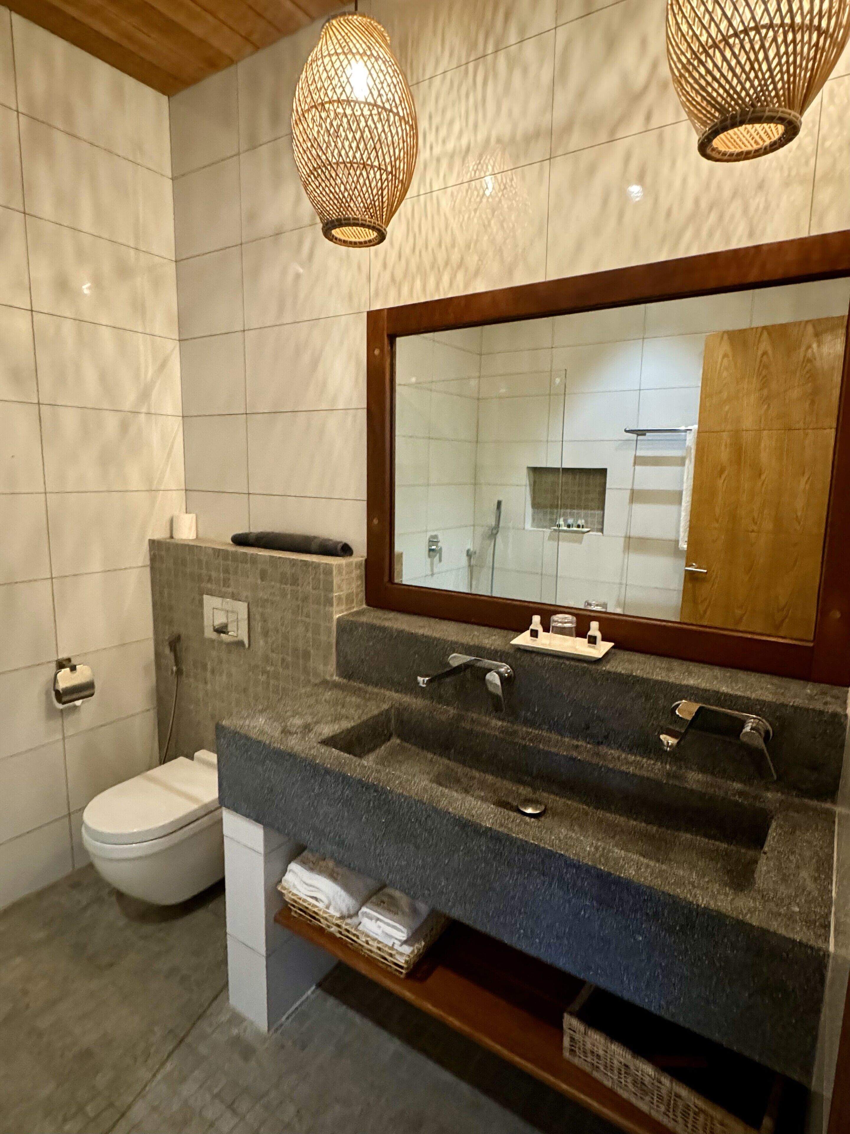 Une salle de bain moderne avec un grand miroir, deux lavabos, des toilettes et une douche.
