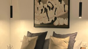 A modern bedroom with a bed, pillows, a bedside table, and a wall-mounted artwork. - Luxury Apartments Collection - The Sand Suite (Passoscuro)