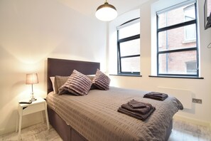 Relax in this serene bedroom with a large bed, bedside table, and stunning city view.
