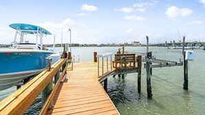 A wooden dock extending into calm water with a boat docked on the left. - Bayfront Cottage -- Close to everything (St. Augustine)
