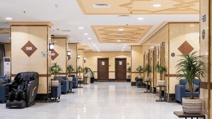 A hotel lobby with a reception area, massage chairs, and potted plants. - Safwat Almiead Hotel (Makkah)