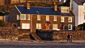 Un pueblo costero con edificios de piedra, un muro de piedra y un mar tranquilo.