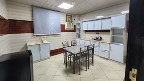 Una cocina compacta con una mesa y sillas, un fregadero, armarios y una ventana con persianas.