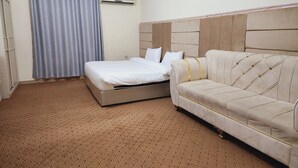 Una habitación de hotel con cama, sofá, cortina y aire acondicionado.