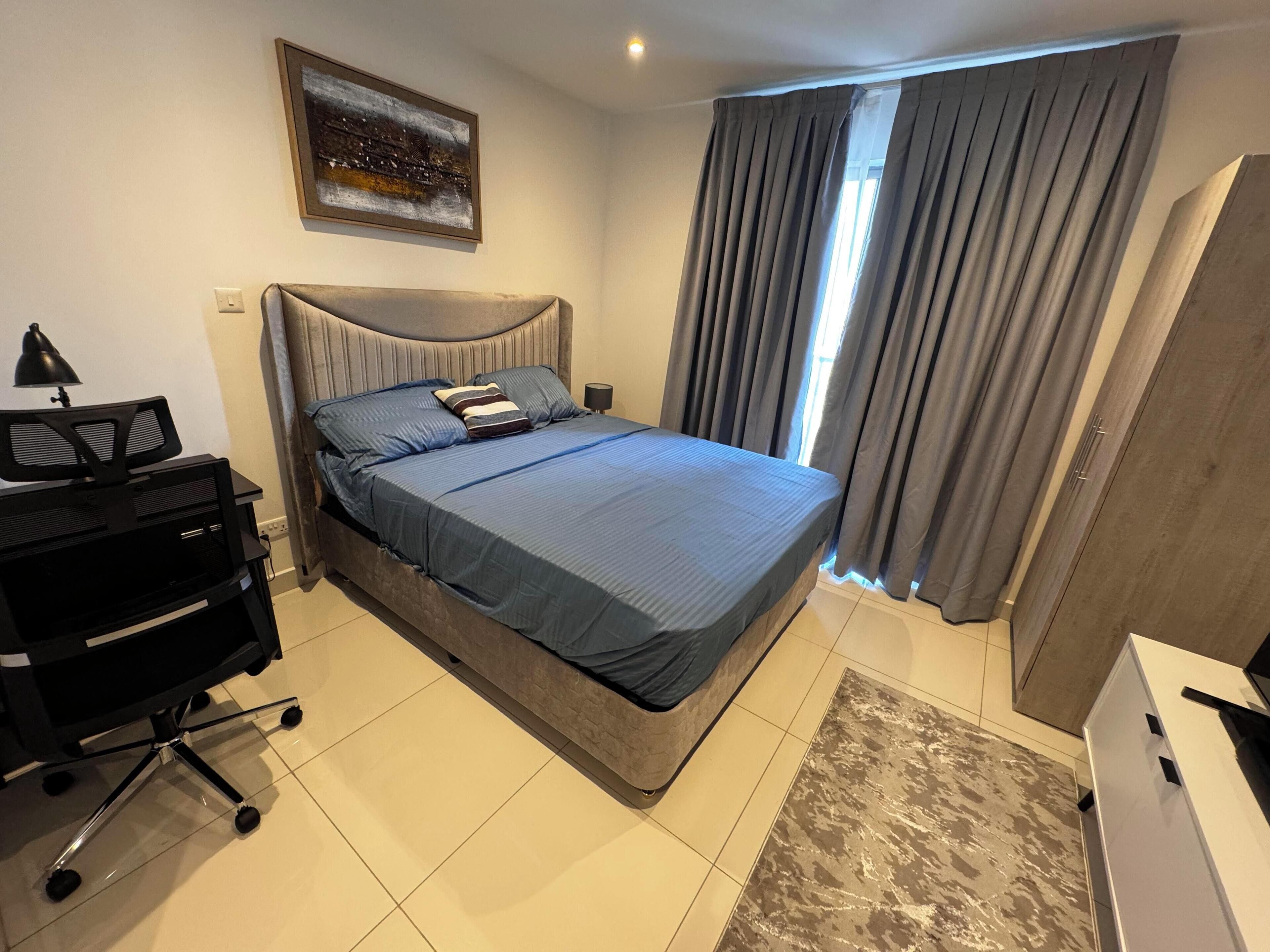 A modern bedroom with a bed, a desk, and a chair.