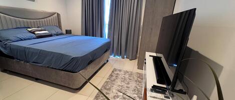 A modern bedroom with a bed, a TV on a stand, and a window with curtains.