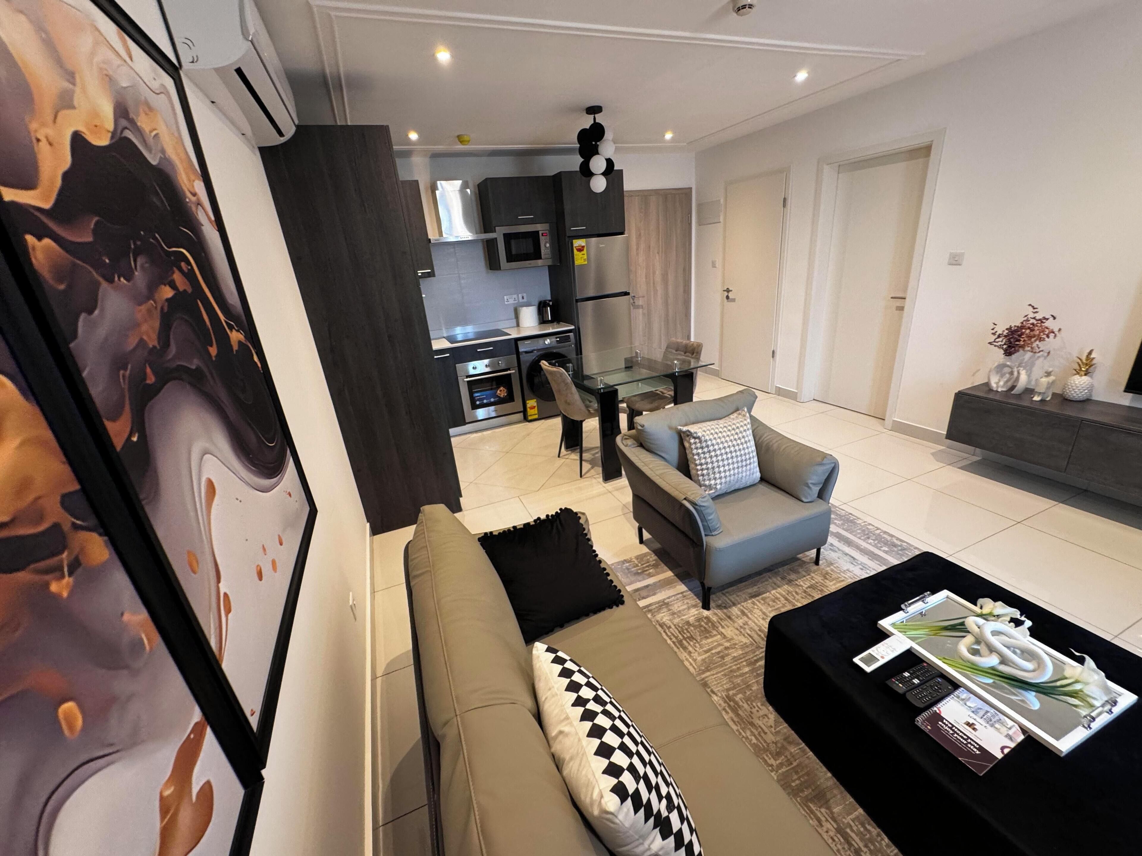 A modern living room with a sofa, a coffee table, and a dining area with a glass table and chairs.