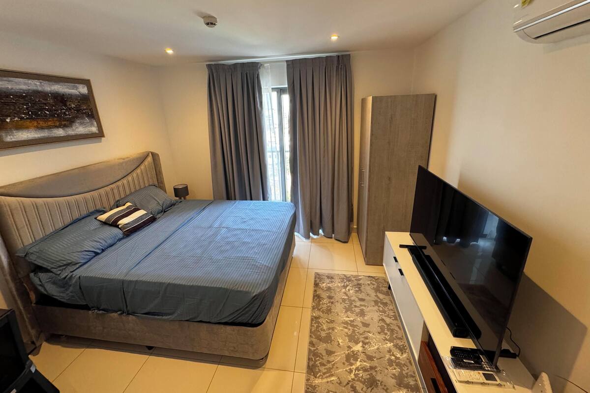 A modern bedroom with a bed, TV, and a desk with a computer.