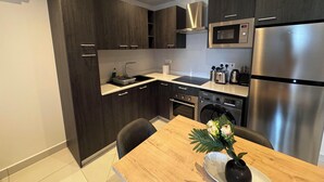 A modern kitchen with dark wood cabinets, stainless steel appliances, a microwave, and a built-in oven. - Loxwood Abode (Accra)
