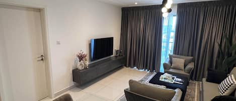 Ein modernes Wohnzimmer mit einem Glastisch, Sofas, einem Fernseher und einem Deckenventilator.