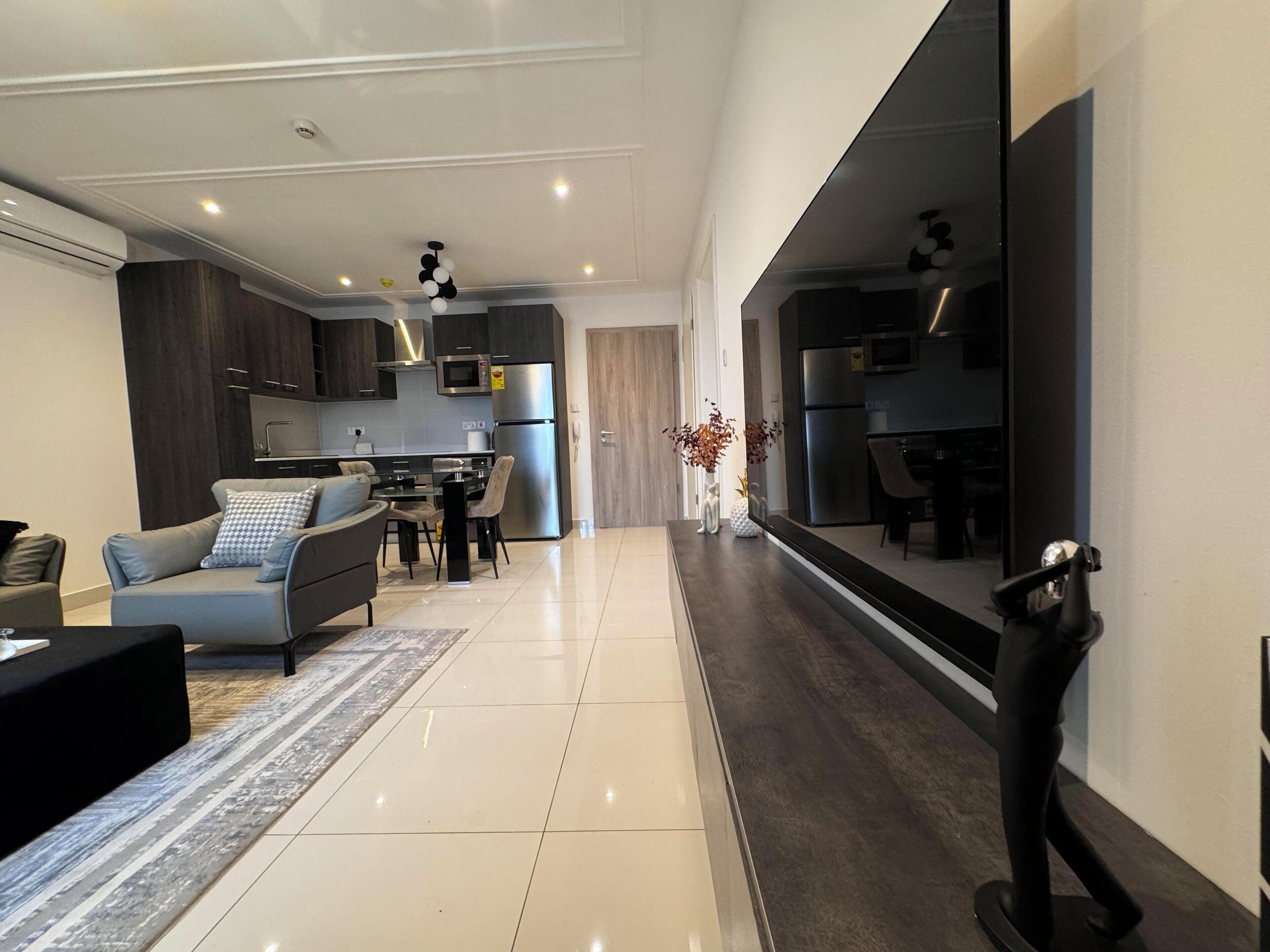 A modern kitchen with stainless steel appliances, a dining area with a table and chairs, and a living room with a sofa and a coffee table.