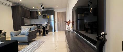 Una cocina moderna con electrodomésticos de acero inoxidable, un comedor con mesa y sillas, y una sala de estar con sofá y mesa de centro.