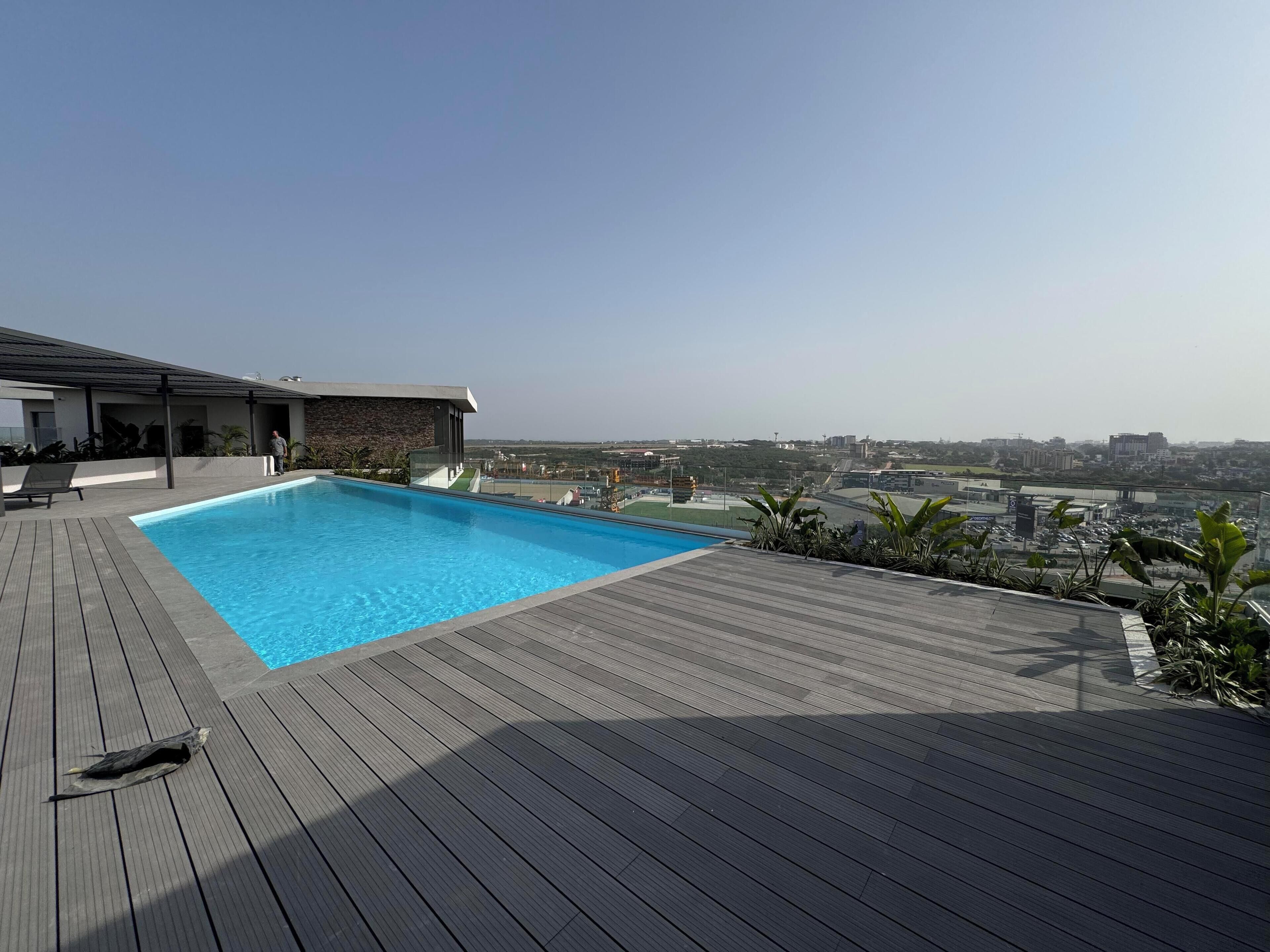 Un área de piscina moderna con vistas despejadas del paisaje urbano al fondo.