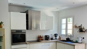 A modern kitchen with white cabinetry, a built-in oven, and a large window providing natural light. - Villa Azur 6 bedrooms and heated pool 20 persons (Le Thoronet)