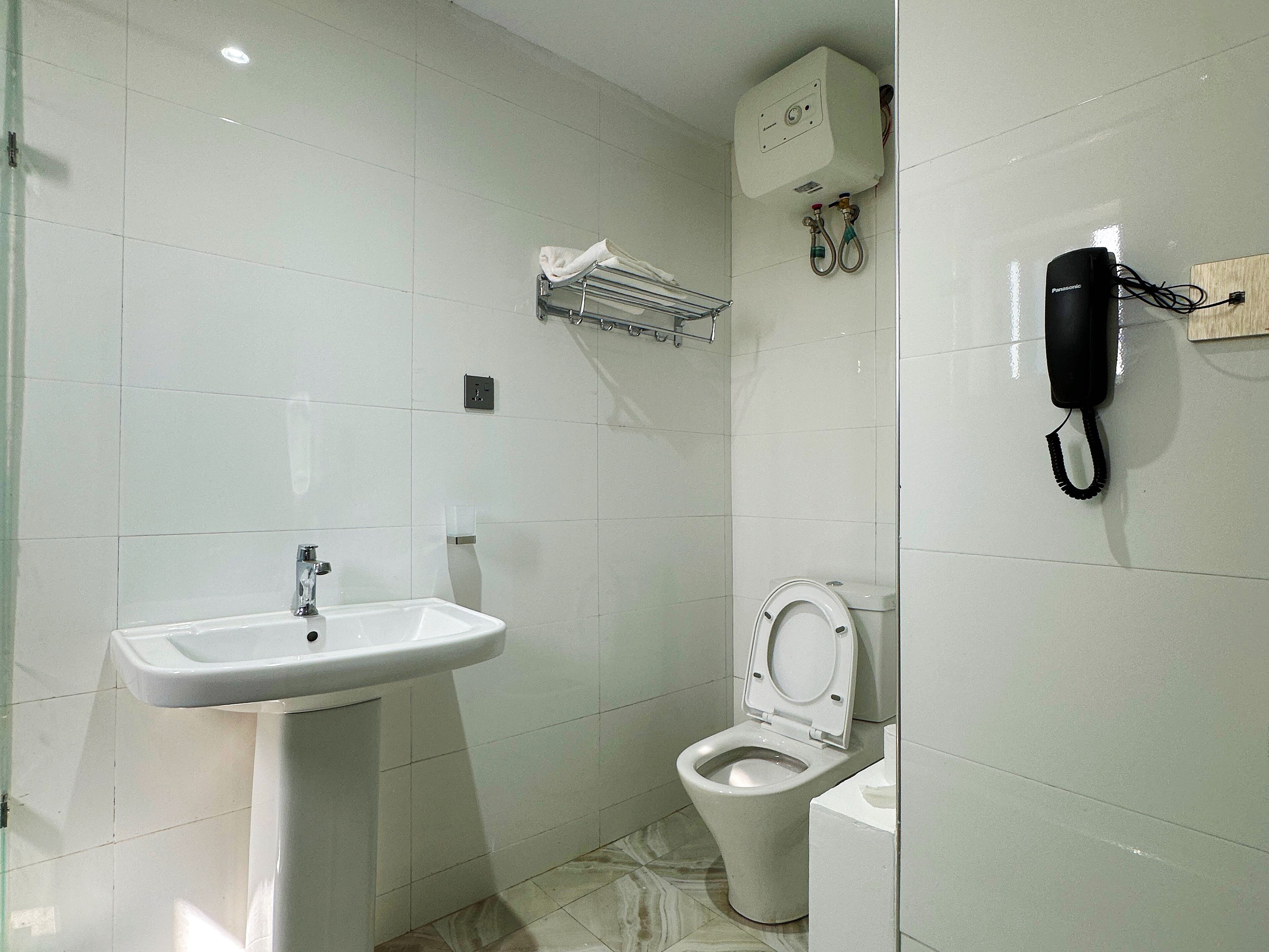 A bathroom with a sink, toilet, and a wall-mounted telephone.