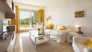 A modern living room with a glass coffee table, white sofas, and a TV. - Ojen Apartment Near Golf (Ojén)