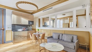 A modern kitchen with a dining area, a sofa, and a coffee table. - Superb AC- 1BDR Ave Montaigne - Arc de Triomphe by Studio Prestige (Paris)