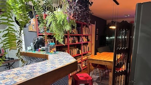 Eine Küche mit gefliestem Rückspritzschutz, einem Holzespeisetisch, roten Hocker und einem Bücherregal voller Bücher.