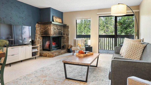 A living room with a stone fireplace, a sofa, a coffee table, and a television. - 6 Mi to Skiing: Condo w/ Balcony in Fraser! (Fraser)