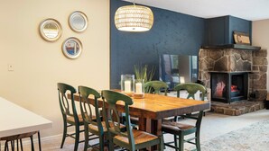 A dining area with a wooden table and chairs, a stone fireplace, and wall-mounted mirrors. - 6 Mi to Skiing: Condo w/ Balcony in Fraser! (Fraser)