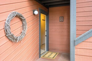 Esterno in legno con ghirlanda, tappeto di benvenuto e una porta con un numero.