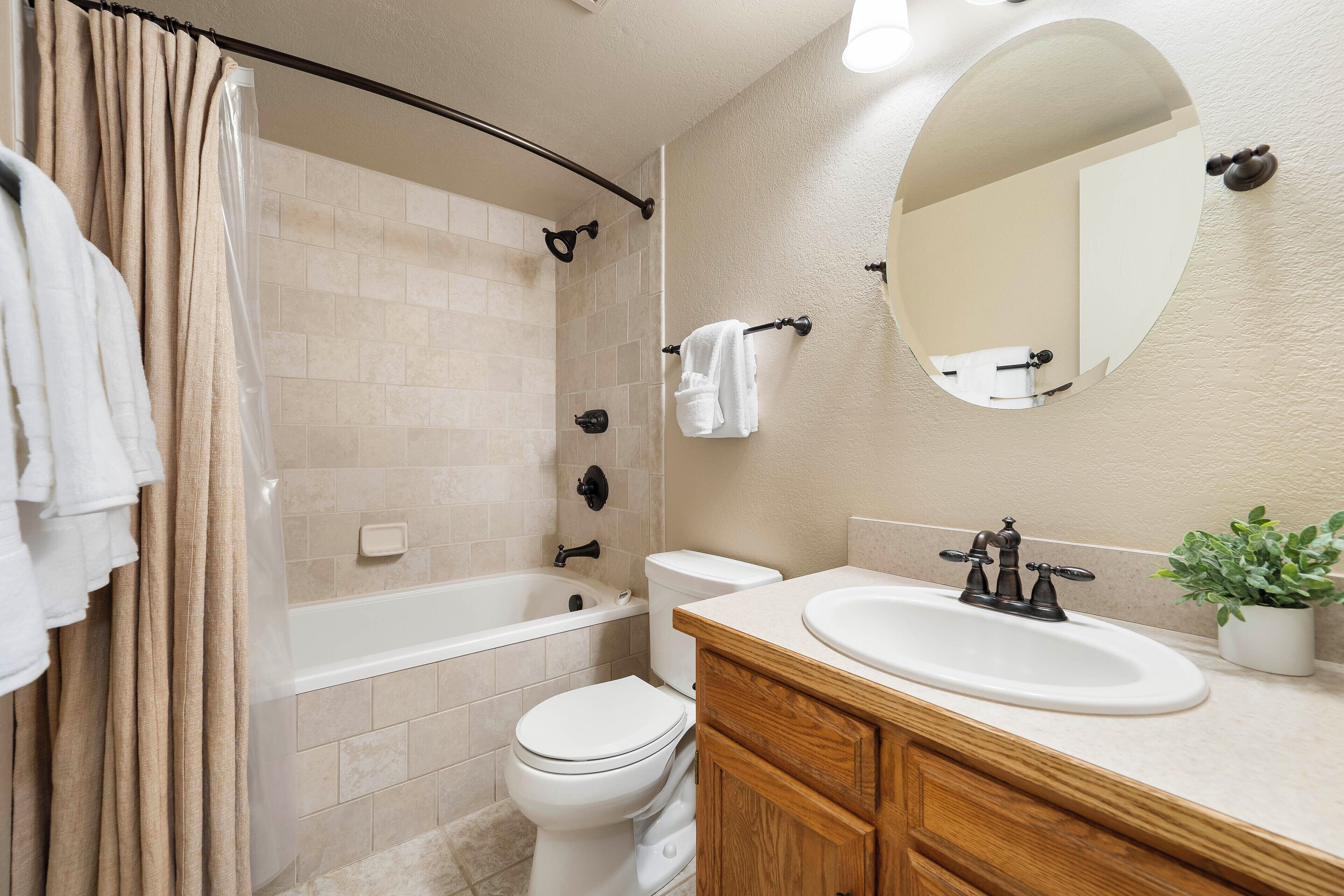 A bathroom with a bathtub, toilet, sink, and mirror.