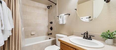 A bathroom with a bathtub, toilet, sink, and mirror.