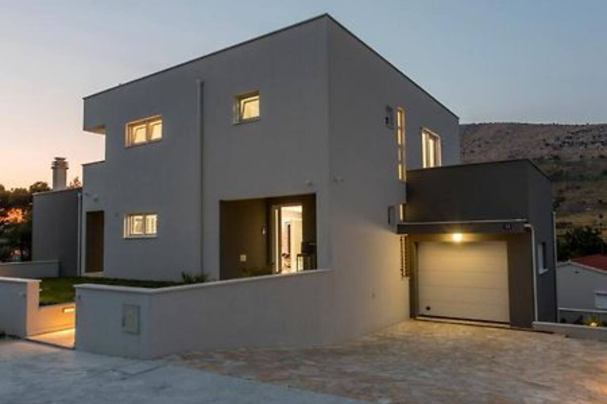Un bâtiment moderne à deux étages, doté d’un toit plat, d’un garage et d’une allée.