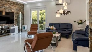 A modern living room with a flat-screen TV, a sofa, two armchairs, and a coffee table. - Modern & Stylish Villa With Private Pool (Omis)