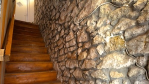 Un escalier en bois, avec un mur en pierre d’un côté.
