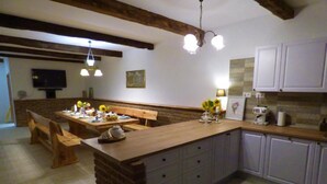 Une cuisine avec un îlot central en bois, des armoires blanches et un mur d’accent en briques.