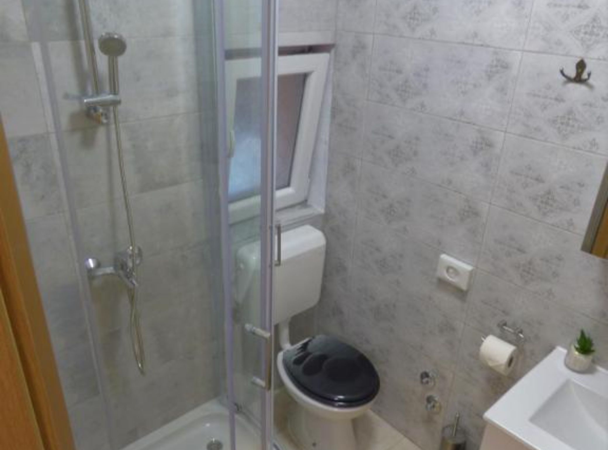 A bathroom with a glass shower enclosure, a toilet, and a sink.