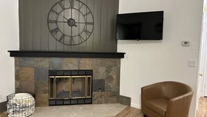A living room with a fireplace, a mounted TV, and a brown leather chair. - Spacious Home + private suite with separate entrance. Family friendly! (Prescott)