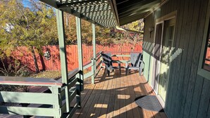 A wooden deck with a covered area, outdoor furniture, and a red fence in the background. - Spacious Home + private suite with separate entrance. Family friendly! (Prescott)