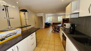 A modern kitchen with white cabinets, a black countertop, and a dining area with a wooden table and chairs.