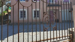 A building with pink walls, multiple windows with purple shutters, and a metal gate.