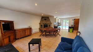 A spacious living area with a stone fireplace, a dining table, and a blue sofa.