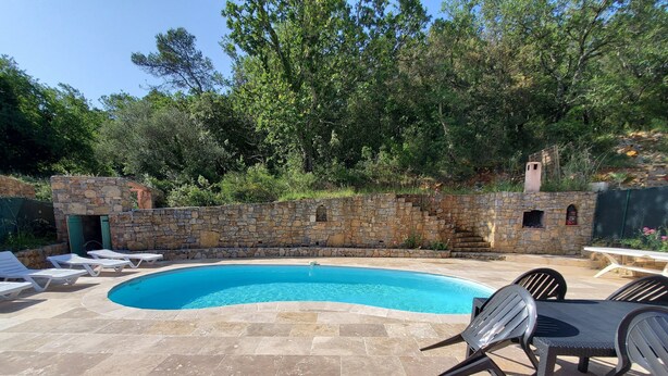 A swimming pool with stone walls and a stone patio.