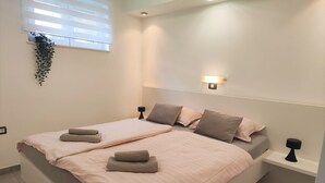 A modern bedroom with a large bed, two bedside tables, and a wall-mounted light fixture. - Modern Crikvenica Apartments With Sea View (Crikvenica)