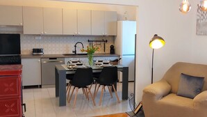 A modern kitchen with white cabinets, a dining table set for four, and a red appliance. - Modern Crikvenica Apartments With Sea View (Crikvenica)