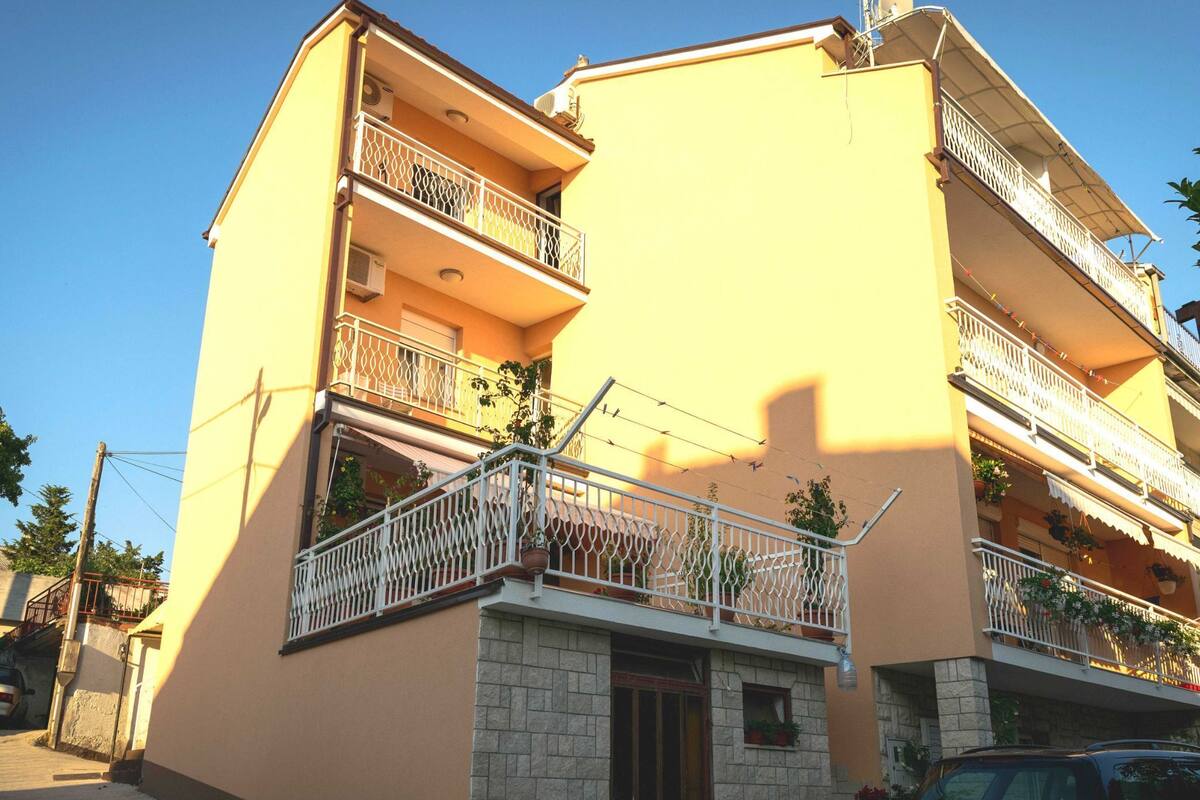 A multi-story building with balconies, a stone base, and a clear sky.