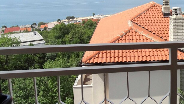 En balkon med udsigt over havet og fjerne bakker.
