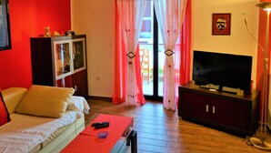A living room with a sofa, a TV, a cabinet, and a window with curtains. - Bright and Stylish Apartment With Balcony and Sea View (Crikvenica)