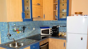 A kitchen with wooden cabinets, a microwave, a coffee maker, and a refrigerator. - Bright and Stylish Apartment With Balcony and Sea View (Crikvenica)