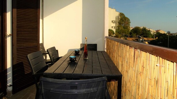 A balcony with a wooden table, two chairs, a bottle, and a bowl. - Bright and Stylish Apartment With Balcony and Sea View (Crikvenica)