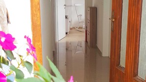 A hallway with a wooden door on the right, a white rocking chair, and a tiled floor. - Seafront Chic Crikvenica Apartments (Crikvenica)