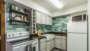 A kitchen with white cabinets, a stainless steel stove, a microwave, and a sink. - The Copper Bungalow (#110) | Walk to Purgatory Ski Lift - Deck, Fireplace (Durango)