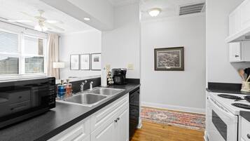 A modern kitchen with a black countertop, stainless steel sink, and white cabinetry.